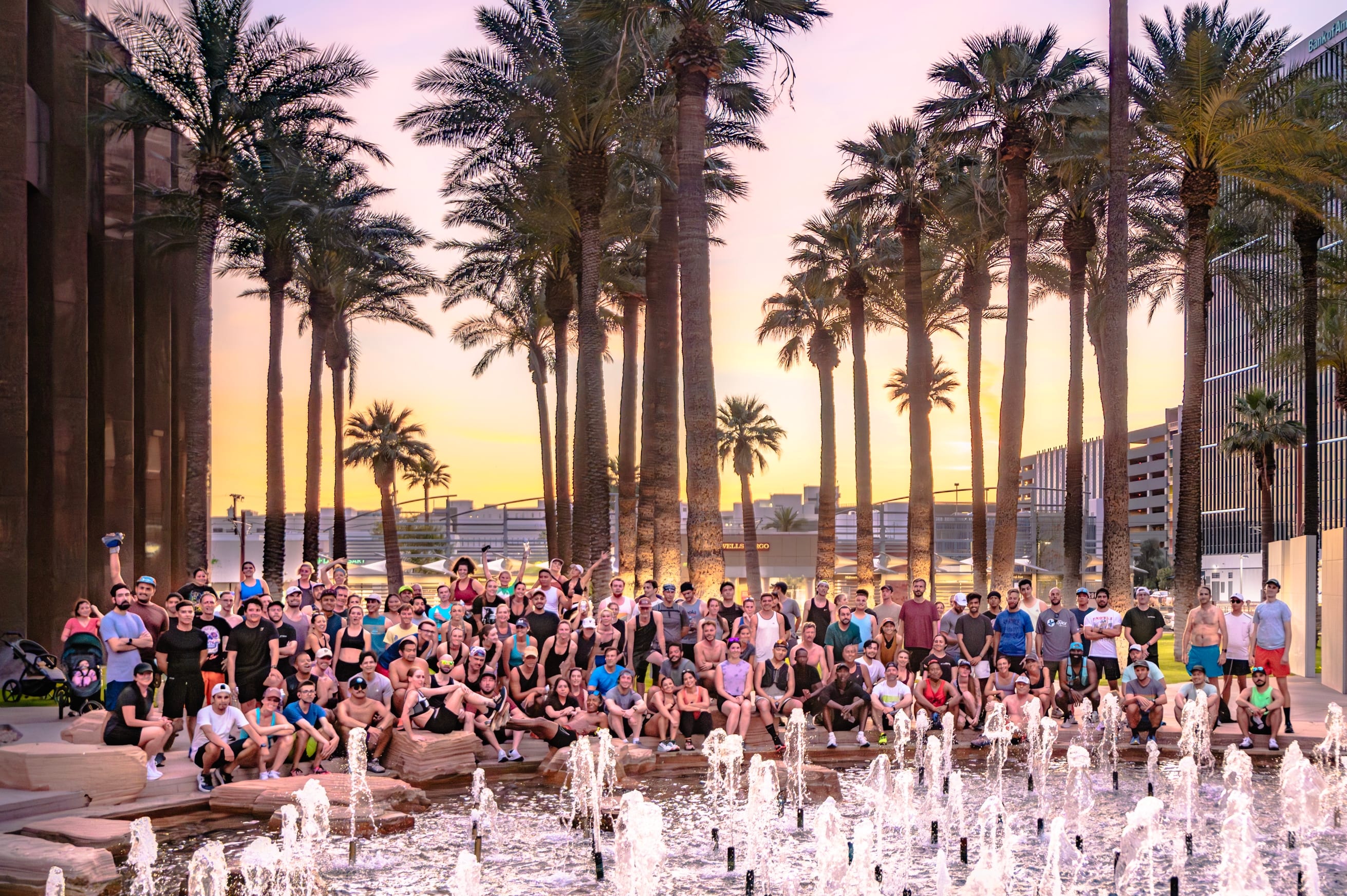 PHX Run Club hosts free weekly events in Phoenix, Arizona. Group of runners behind a fountain at sunset.